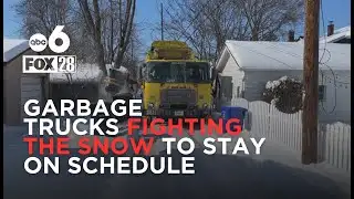 Garbage trucks drive through snowy, narrow alleys to continue service