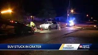SUV gets stuck in crater sized pothole