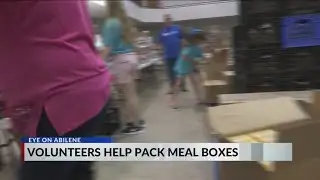 volunteers help pack meal boxes